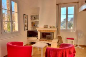 Appartement Villa Tamaris, vue mer في لا سين سور مير: غرفة معيشة بها موقد وكراسي حمراء