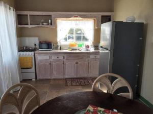 a kitchen with a refrigerator and a table with chairs at Cozy 2 bedroom beachfront cabin in Canouan