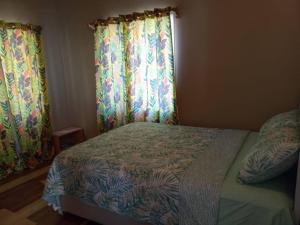 a bedroom with a bed and curtains and a window at Cozy 2 bedroom beachfront cabin in Canouan