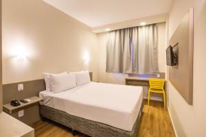 Habitación de hotel con cama y silla amarilla en Transamerica Fit Rio Verde, en Rio Verde