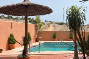 a swimming pool with an umbrella and some plants at La Barossa in Algeciras