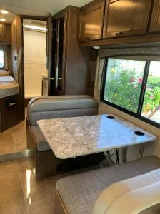 Blick auf einen Wohnwagen mit einem Tisch und einem Fenster in der Unterkunft AJ-XL RV Rental in Reseda