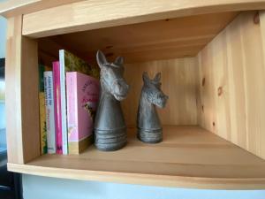ein Bücherregal mit zwei Figuren eines Pferdes darauf in der Unterkunft Lagerhaus Gabriel in Zweibrücken