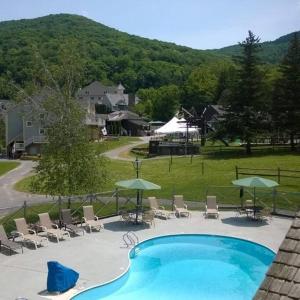 汉考克Gorgeous New Zen Suite Sleeps 4-Ski On Off Jiminy的配有椅子和遮阳伞的游泳池