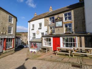 a building with a red door and benches in front of it at 1 The Stables in Alston