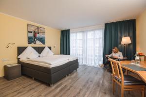 una mujer sentada en una habitación de hotel con una cama en Hotel am Park en Hückelhoven