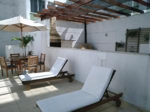 une terrasse avec des chaises, une table et un parasol dans l'établissement Apartamento em Cabo Frio, à Cabo Frio