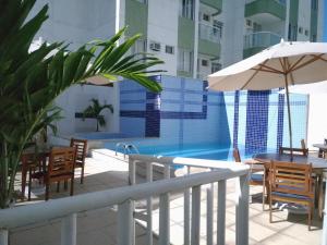uma piscina com mesas e cadeiras e um guarda-sol em Apartamento em Cabo Frio em Cabo Frio