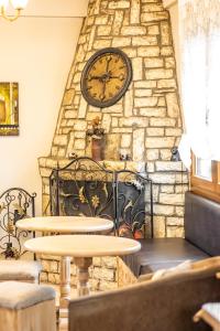 a large clock on a stone wall with two tables at Enastron in Kalavrita