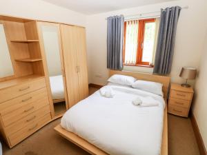 a bedroom with a bed with white sheets and a mirror at 15 Sovereign House in Milford Haven