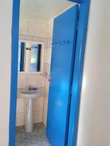 a bathroom with a sink and a blue door at Pousada Oceano Azul in Ilha do Mel