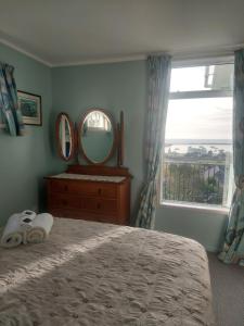 a bedroom with a bed and a mirror and a window at Oamaru Green Cottage in Oamaru