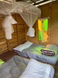 a room with three beds in a wooden cabin at Khaokhopimphupha farmstay เขาค้อพิมภูผาฟาร์มสเตย์ ไม่มีไฟฟ้า น้ำจากน้ำตกธรรมชาติ Low cabon with Sustainability cares in Ban Non Na Yao