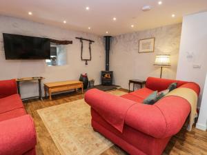 a living room with two red couches and a tv at Stabla in Pwllheli