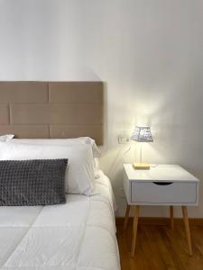 1 dormitorio con cama blanca y mesita de noche con lámpara en Filo Guest House en Perugia