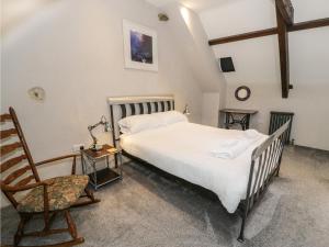 a bedroom with a large bed and a chair at Stabla in Pwllheli