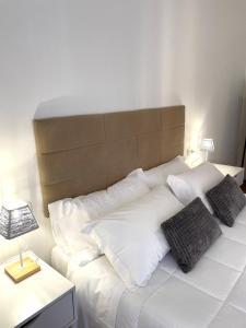 Filo Guest House في بيروجيا: سرير أبيض مع وسائد بيضاء و اللوح الأمامي بني