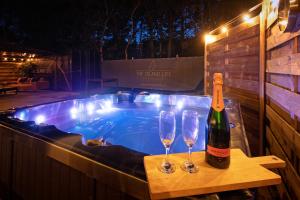 a bottle of wine and two wine glasses next to a hot tub at The island life Texel - Wellness in De Koog