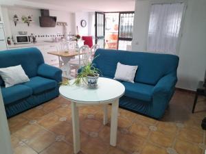 una sala de estar con 2 sofás azules y una mesa. en Alojamiento Casa Piano, en Mairena del Aljarafe
