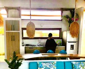 uma mulher de pé numa cozinha com uma mesa em Acuarela del Mar em Dibulla