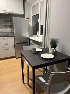 a black table and chairs in a kitchen with a refrigerator at Aizkraukle Penthouse apartment in Aizkraukle +5 photos