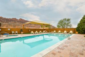 a large swimming pool with chairs and a umbrella at Rim Village M4 in Moab