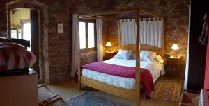 um quarto com uma cama de dossel em madeira com lençóis roxos em El Folló Turisme Rural em Tagamanent