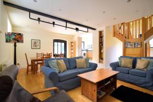 una sala de estar con sofás azules y una mesa. en Yard Cottage en Lyme Regis