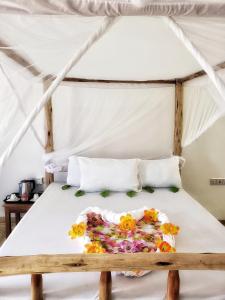 Una cama con flores en una habitación en Serenity 2 - Jambiani en Jambiani