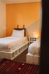 two beds in a room with orange walls at Nomads Hotel Petra in Wadi Musa
