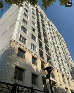 a tall white building with a lot of windows at Апартаменты в центре Бишкека in Bishkek