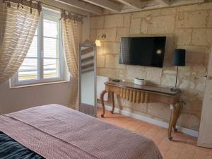 - une chambre avec un lit et une télévision murale dans l'établissement Fontevraud Les Chambres, à Fontevraud-l'Abbaye