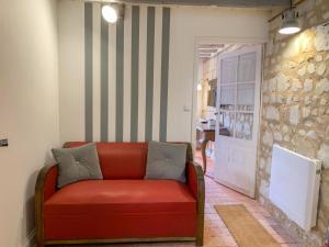 un sofá rojo sentado en una habitación con una pared en Fontevraud Les Chambres, en Fontevraud-l'Abbaye