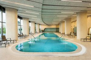 a large swimming pool in a hotel lobby with chairs at Tasigo Eskisehir in Eskisehir