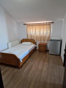 una camera con letto, finestra e pavimenti in legno di Hotel Restaurant Savoja a Pogradec