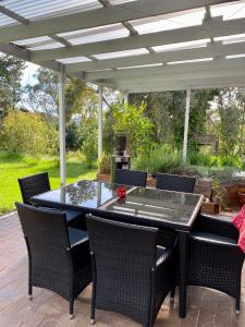 a patio with a table and chairs under a pergola at Amongst the Vines Deluxe Retreat in Blewitts Springs