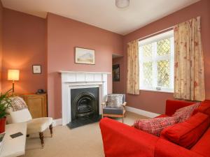 a living room with a red couch and a fireplace at Gable Lodge in Great Malvern