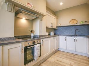 una cocina con armarios blancos y fregadero en Gable Lodge en Great Malvern