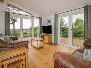 a living room with couches and a television and sliding glass doors at 11 Faraway Fields in Liskeard