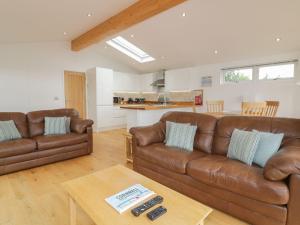 a living room with two brown leather couches and a table at 11 Faraway Fields in Liskeard