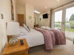 a bedroom with a bed with a lamp and a window at 11 Faraway Fields in Liskeard