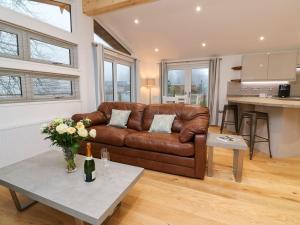 a living room with a brown leather couch and a table at 9 Faraway Fields in Liskeard