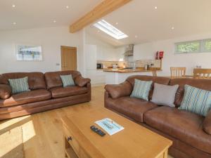 a living room with brown leather couches and a table at 2 Faraway Fields in Liskeard