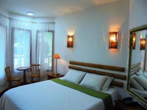 um quarto com uma cama branca e um espelho em Pousada Náutilus em Ilhabela