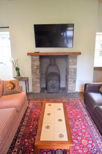 a living room with a fireplace with a flat screen tv at Grooms Cottage in Carsethorn