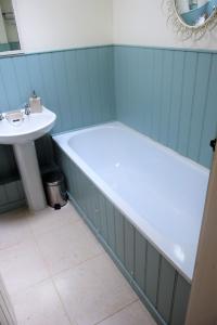 a bath tub and a sink in a bathroom at Grooms Cottage in Carsethorn