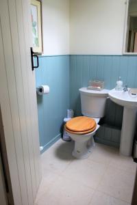 a bathroom with a toilet with a wooden seat and a sink at Grooms Cottage in Carsethorn