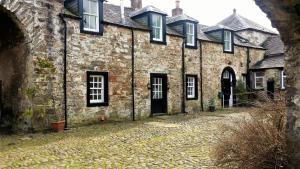 an old stone building with black windows and a driveway at Grooms Cottage in Carsethorn