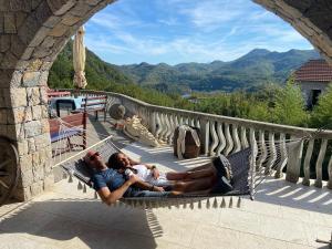 two people laying on a hammock on a balcony at Skadar Lake Family Resort in Rijeka Crnojevića