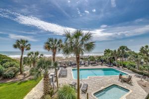 an image of a swimming pool with palm trees and the beach at Carolina Dunes - 503 in Myrtle Beach